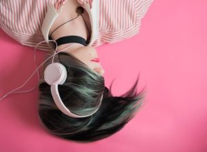 Mädchen mit Kopfhörern auf rosarotem Hintergrund